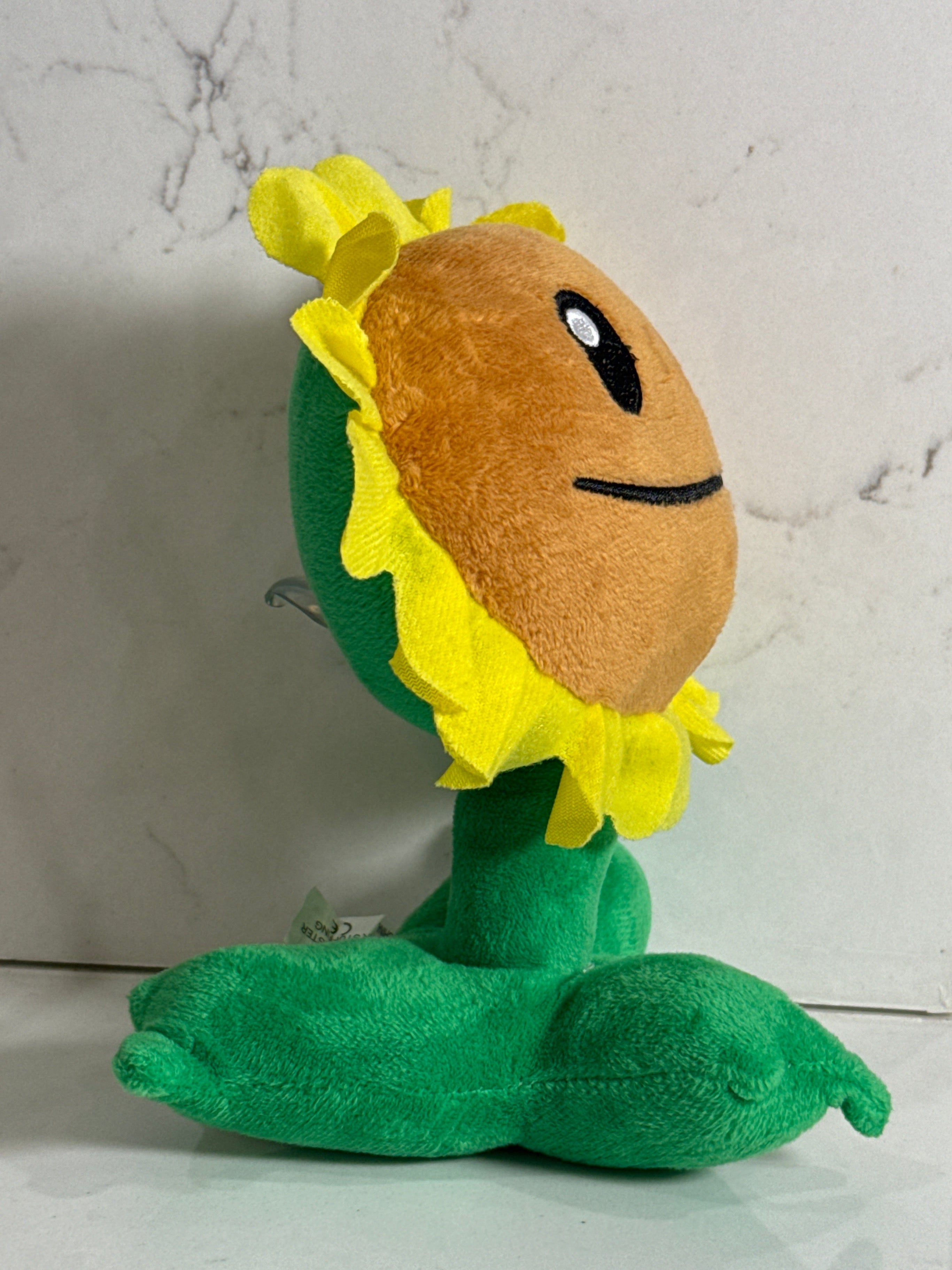 Plush toy resembling a sunflower with a face on a marble surface